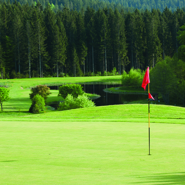 Eine rote Fahne auf dem hügeligen Golfplatz