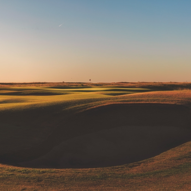 Surreal anmutende Graslandschaft mit großem Krater im Vordergrund