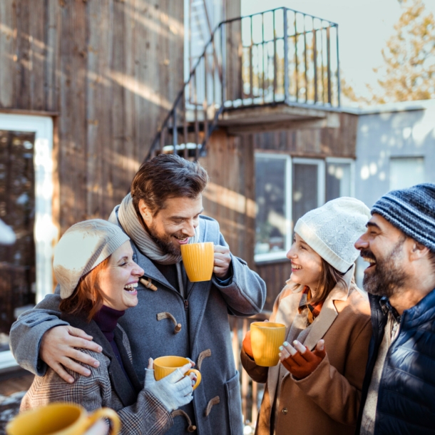 Freunde stehen im Winter vor eine Holzhütte und lachen und reden miteinander