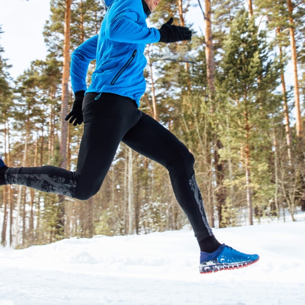 Ein Mann joggt im verschneiten Wald.