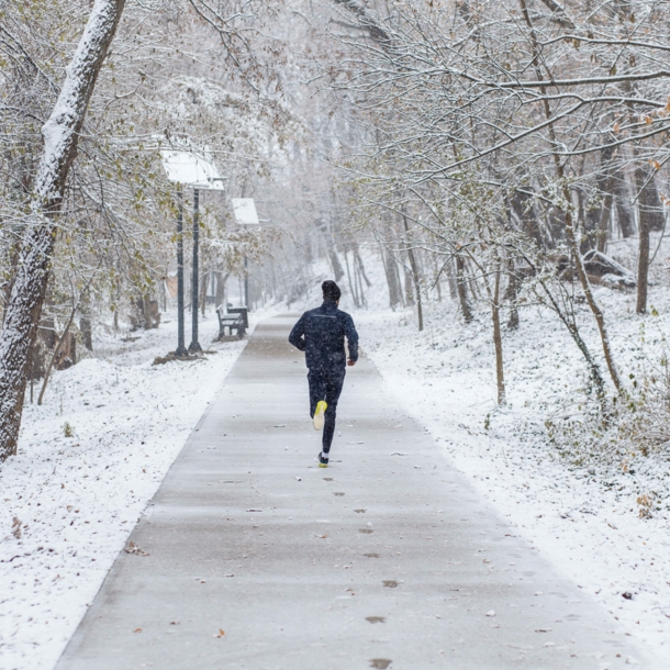 Mann von hinten fotografiert beim Joggen durch eine Winterlandschaft