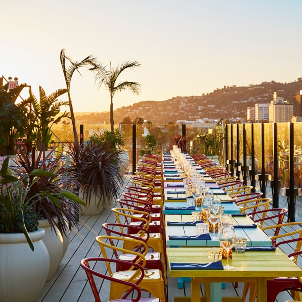 Dachterrasse mit Pflanzen und bunten, gedeckten Tischen im Sonnenuntergang