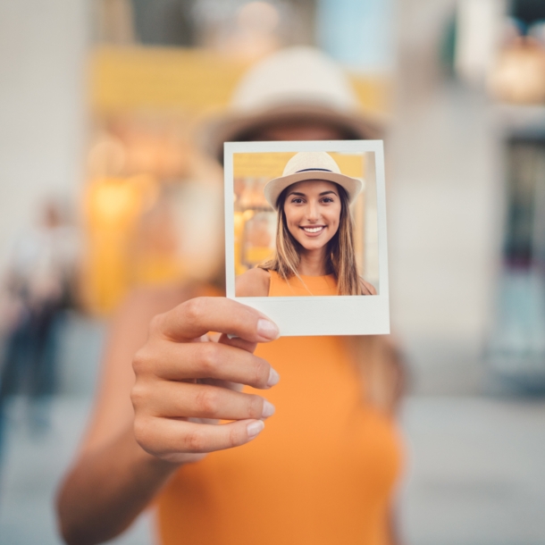 Eine junge Frau hält ein Polaroid in der Hand mit einem Selbstportrait