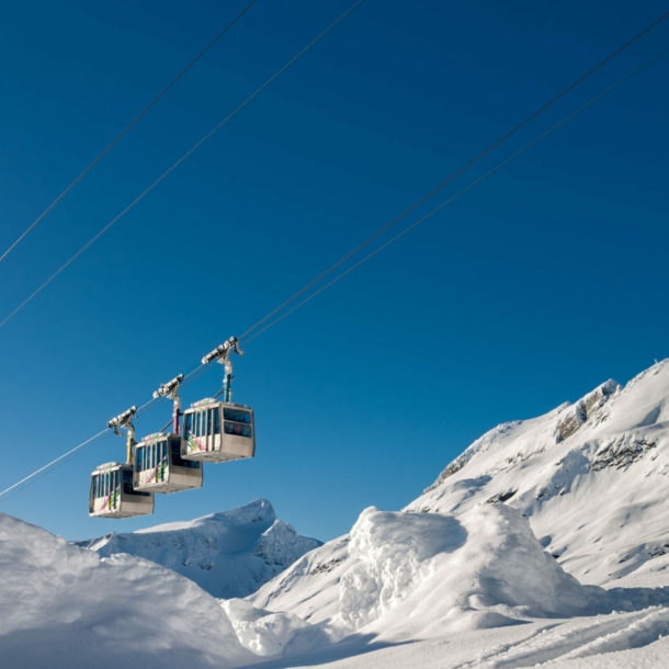 Eine Seilbahn vor blauem Himmel und schneebedeckten Bergen