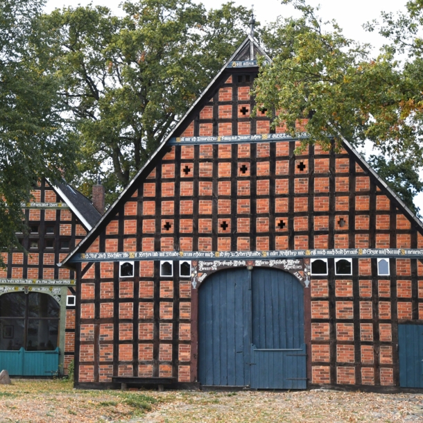 Zwei Fachwerkhäuser mit blauen Toren, daneben Bäume