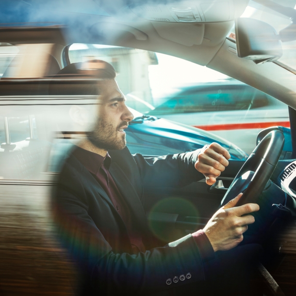 Ein Mann in einem Auto hebt seinen Arm, um auf die Armbanduhr zu schauen