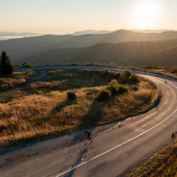 Ein Radfahrer auf einer einsamen Straße im Sonnenuntergang.