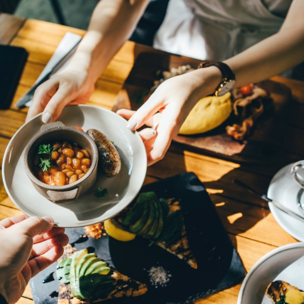 Hände reichen bei einem Brunch in Berlin eine Schale mit Essen