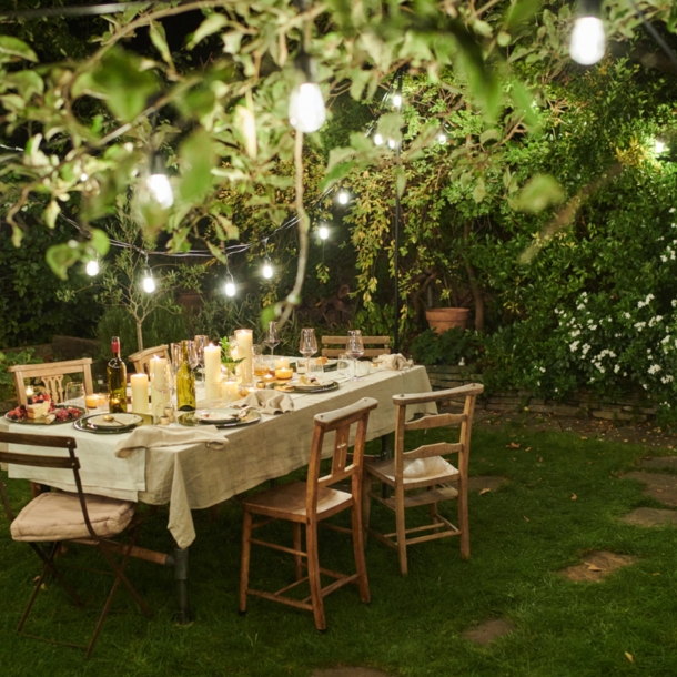 Ein gedeckter Tisch in einem Garten mit stimmungsvoller Beleuchtung bei Nacht