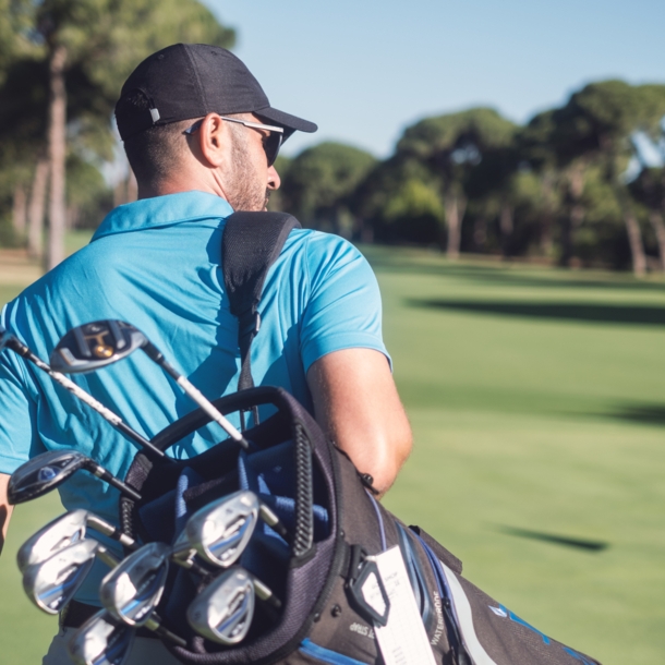 Golfspieler mit Golftasche läuft über einen Golfplatz