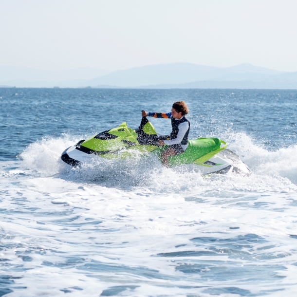 Eine Person fährt mit grünem Jetski auf dem offenen Meer