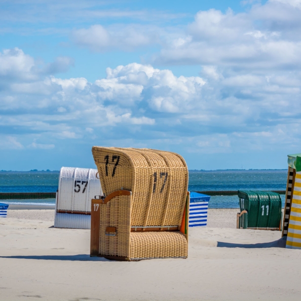 Strandkörbe an einem menschenleeren Sandstrand vor blauem Himmel