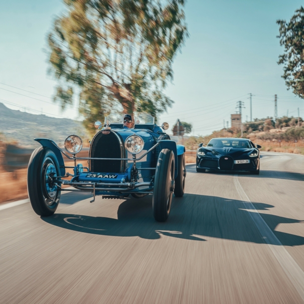 Ein Oldtimer und ein moderner Sportwagen auf einer Straße