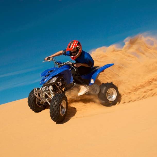 Ein Mann fährt auf einem Quad eine Sanddüne hinunter