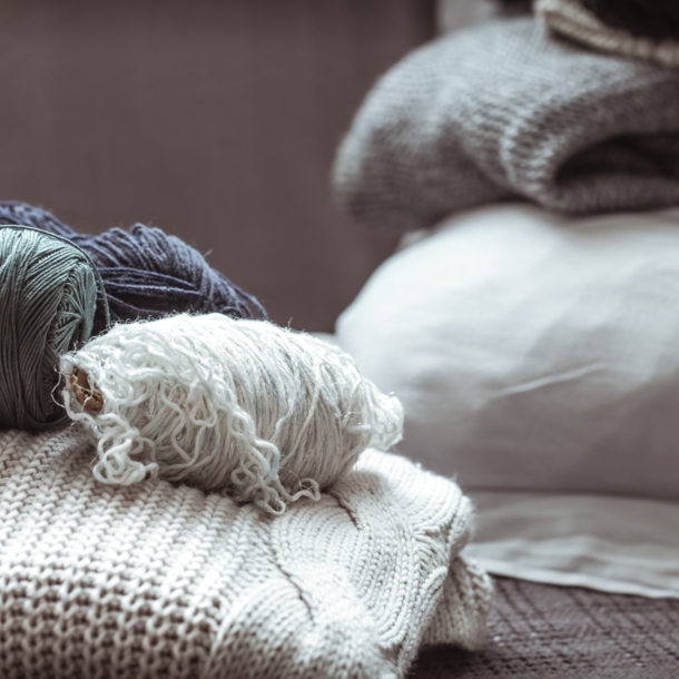 Arrangement aus mehreren Garnknäulen auf einem Strickpullover.