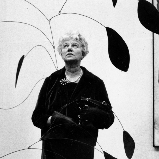 Porträt von Peggy Guggenheim, die in einer Kunstausstellung ein Mobile betrachtet