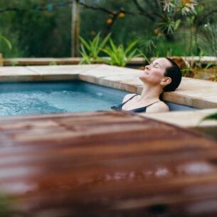 Eine Frau liegt entspannt in einem Whirlpool in der Natur