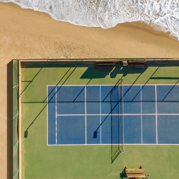 Drohnenansicht des Tennisplatzes am Sand und Meer.