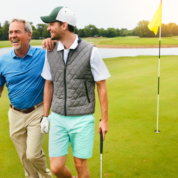 Zwei Golfspieler laufen über einen Golfplatz und lachen