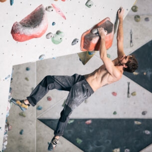 Ein durchtrainierter Mann an einer Kletterwand in einer Boulderhalle