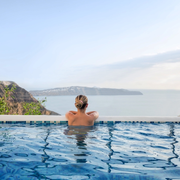 Rückansicht einer Frau in einem Infinitypool mit Blick aufs Meer