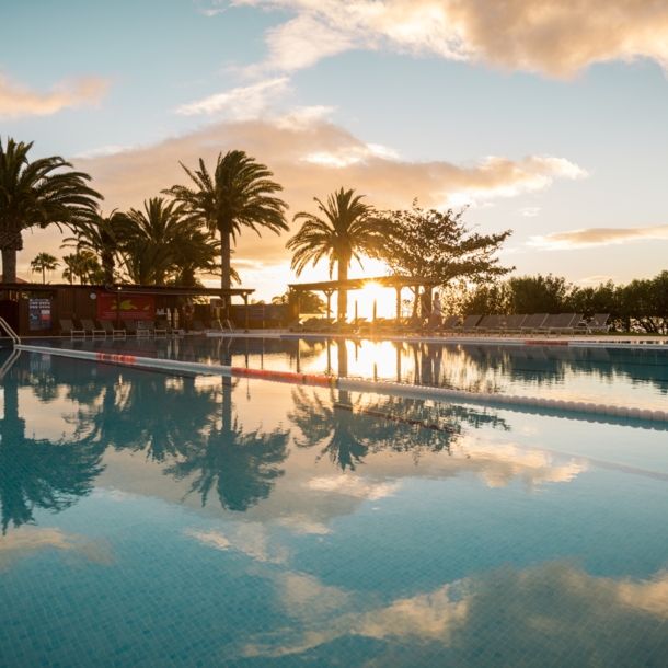 Ein großer Außenpool in einer Hotelanlage am Meer bei Sonnenuntergang