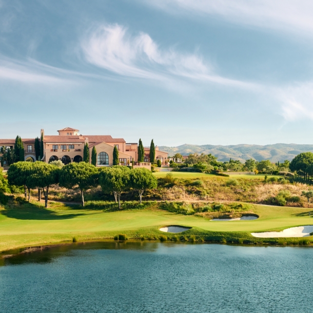 Ein Klubhaus auf einem Golfplatz mit Bäumen und einem See