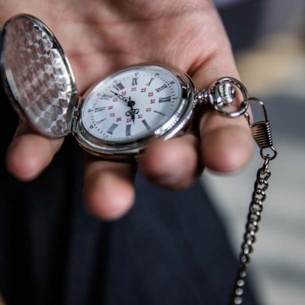 Eine Person hält eine aufgeklappte Taschenuhr in der Hand