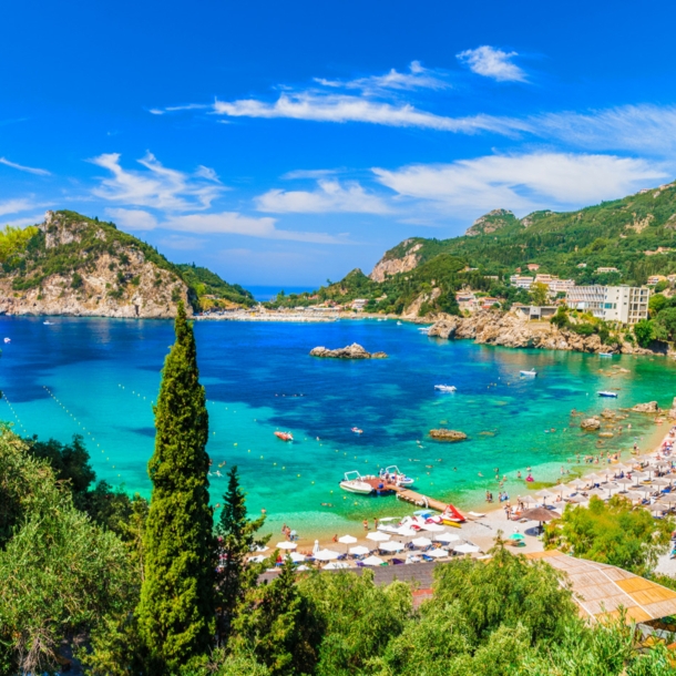 Blick über den Strand von Paleokastritsa mit türkisem Wasser und grüner Umgebung