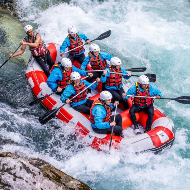 Acht Personen beim Wildwasser-Rafting in einem Schlauchboot