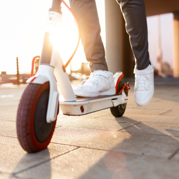 Nachaufnahme eines Rollers, auf dem ein Mann mit weißen Turnschuhen steht, Symbolbild