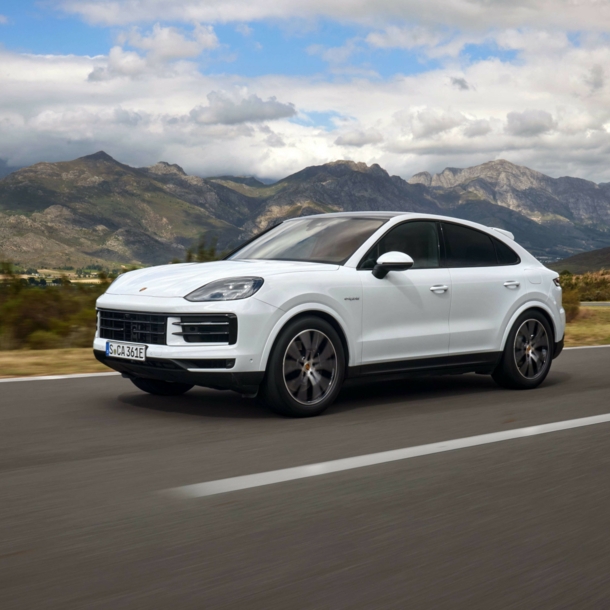 Ein weißer Porsche Cayenne auf einer Straße, im Hintergrund Berge