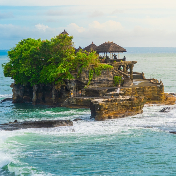 Ein Tempel und mehrere Bäume auf einem Felsen im Meer