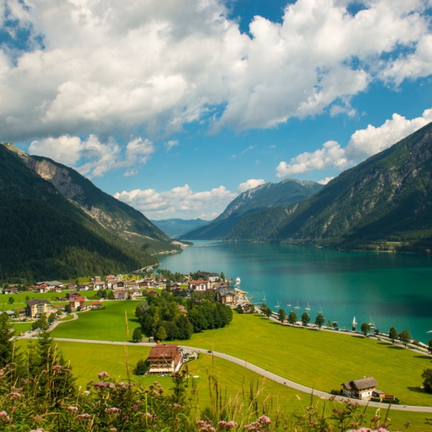 Ein türkisfarbener See zwischen Bergen und einem kleinen Dorf