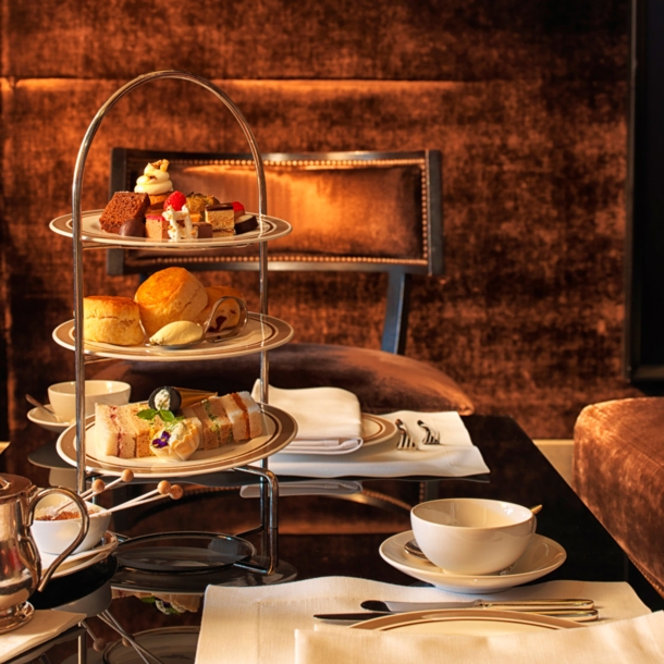 Eingedeckter Tisch zur Teatime mit Gebäck und Süßspeisen auf einer Etagere.