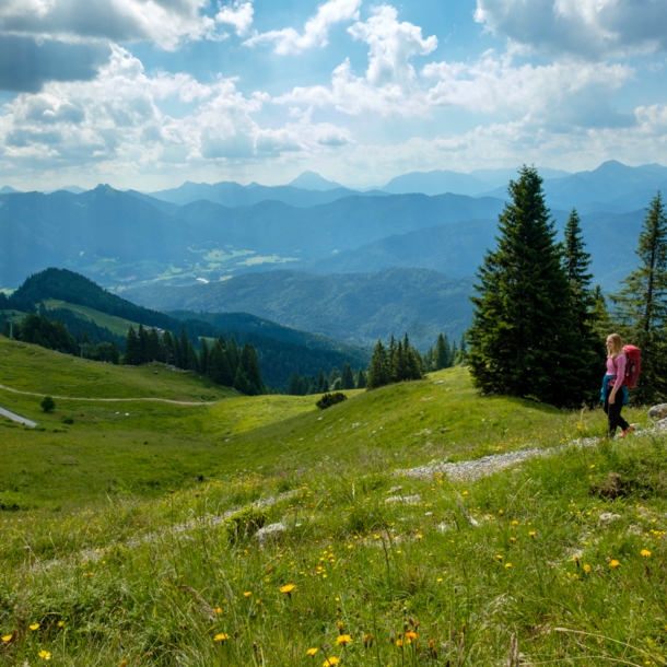 Ein wanderndes Paar mit Rucksäcken auf einem Weg inmitten einer grünen Berglandschaft.