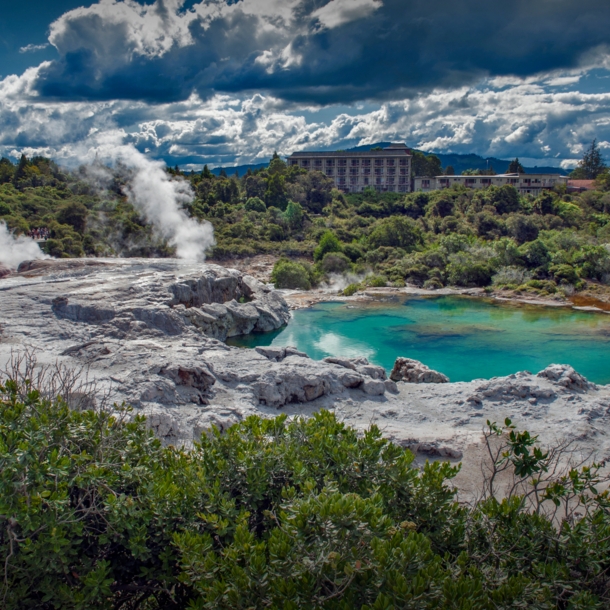 Blick auf Landschaft mit dampfenden Geysiren und grünblauem Wasser