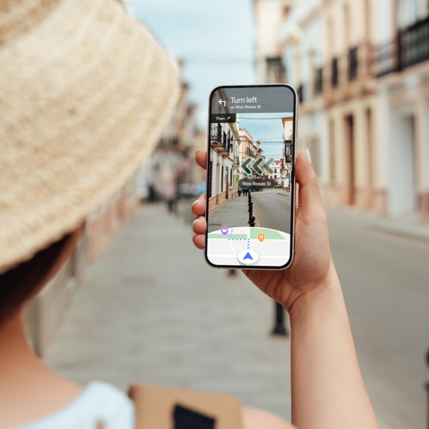 Eine Frau navigiert mit Blick auf ihr Smartphone per Live View von Google Maps durch eine Straße.