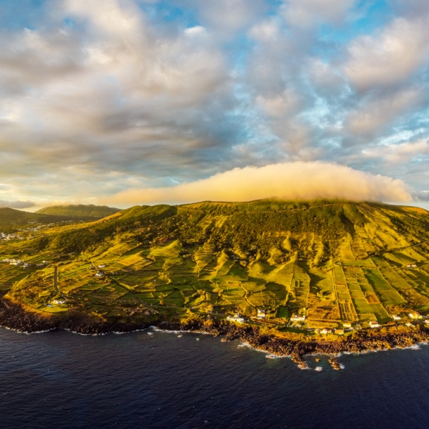 Luftaufnahme der Vulkaninsel Graciosa mit sanften, grünen Hügellandschaften bei Sonnenuntergang.