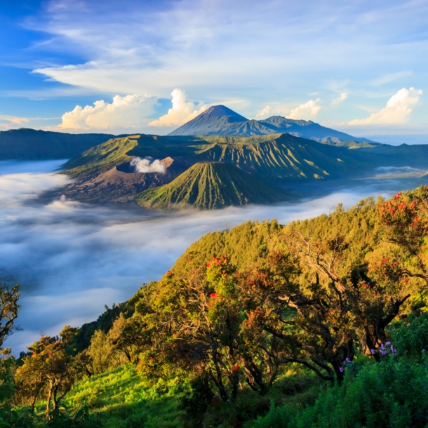 Landschaftsaufnahme über die indonesische Insel Java mit Vulkanen im Hintergrund.