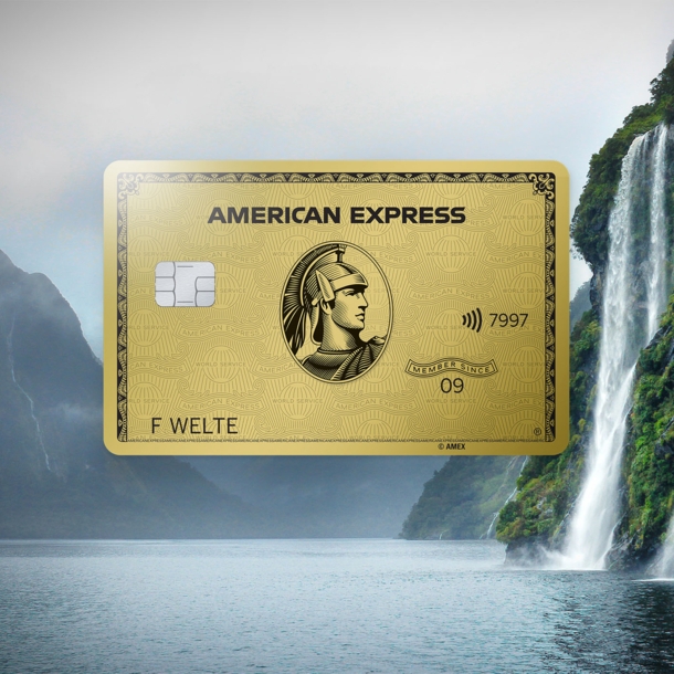 Fotocollage mit einer goldenen Kreditkarte von American Express vor einer nebeligen Berglandschaft an einem See mit Wasserfall.