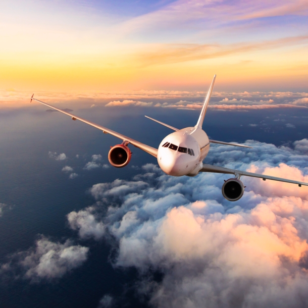 Ein Flugzeug fliegt über den Wolken bei Sonnenuntergang.