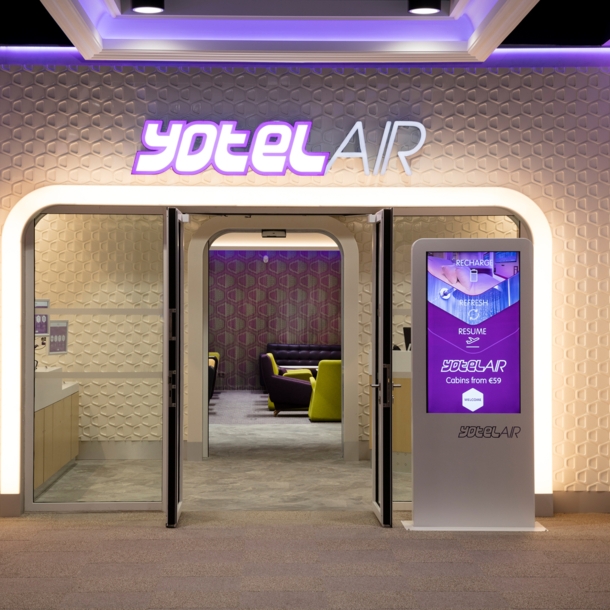 Beleuchteter Eingang zu einer modernen Flughafenlounge von YotelAir.