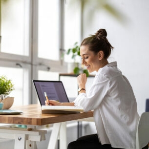 junge Frau arbeitet zuhause mit Laptop und Notizbuch