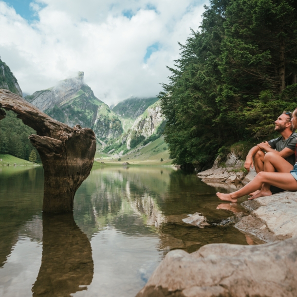 Ein Paar sitzt am Ufer eines idyllischen Bergsees im Sommer.