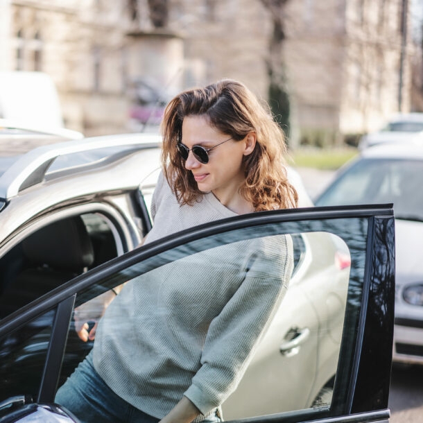 Frau mit Sonnenbrille steigt in parkenden PKW ein