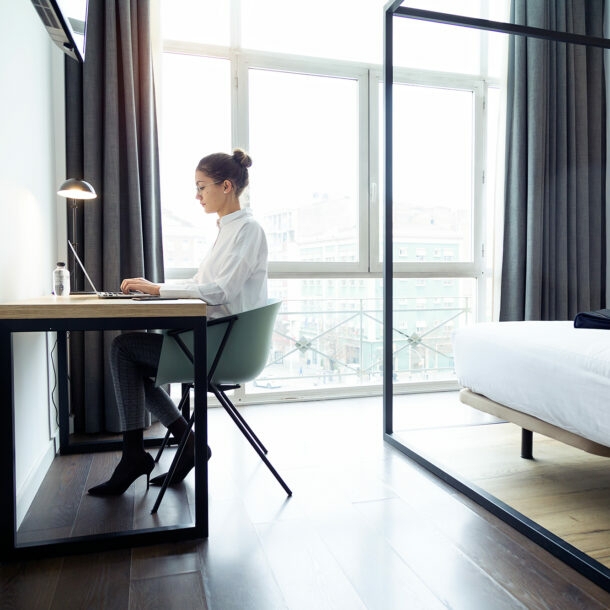 Junge Geschäftsfrau arbeitet am Laptop in ihrem Hotelzimmer