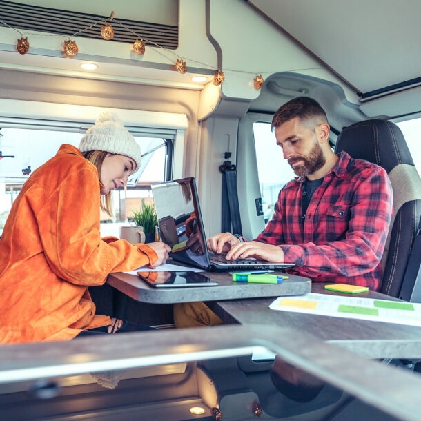 Junges Paar arbeitet am Laptop im Wohnmobil