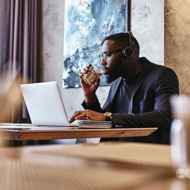 Geschäftsmann mit Kopfhörer arbeitet in einer Hotellobby am Laptop