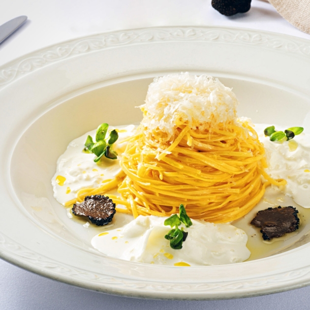 Spaghetti-Gericht mit Burrata und Trüffel, edel angerichtet auf einem weißen Teller.